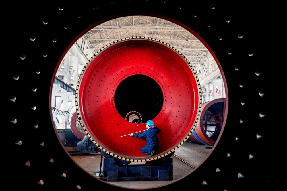An employee measures a newly manufactured ball mill machine at a factory in Nantong, Jiangsu province, China. — Reuters