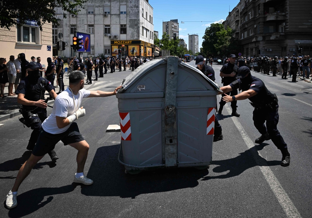 A protester tries to prevent the police from removing a garbage bin blocking a street, in Belgrade. — AFP