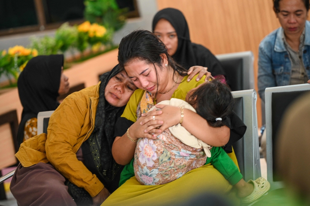 Family members and relatives wait for updates on the search operation, at Ketapang Port in Banyuwangi. — AFP