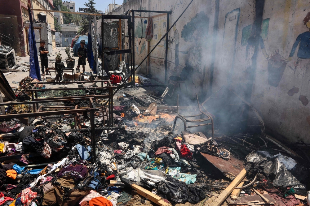 Children look at smouldering debris at Mustafa Hafez school, following an overnight Israeli strike in Gaza. — AFP