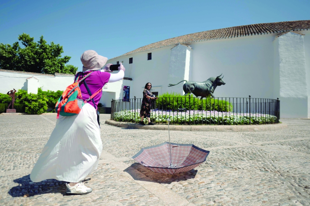 A woman leaves her umbrella while she takes a picture in Ronda, southern Spain during the first heatwave of the summer. — AFP