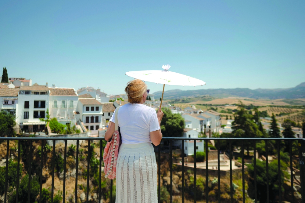 A woman uses a parasol to shield herself from the sun while looking at the landscape in Ronda, southern Spain, as the first summer heatwave continues to scorch the country. — AFP