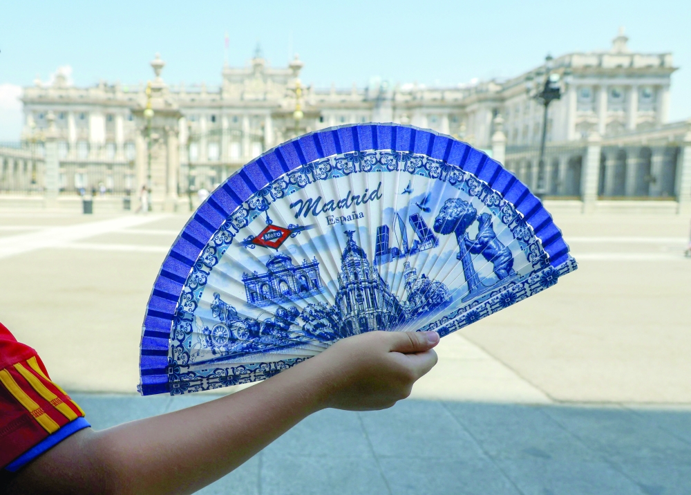 A person holds a hand fan in front of the Royal Palace during a heatwave in Madrid. — AFP