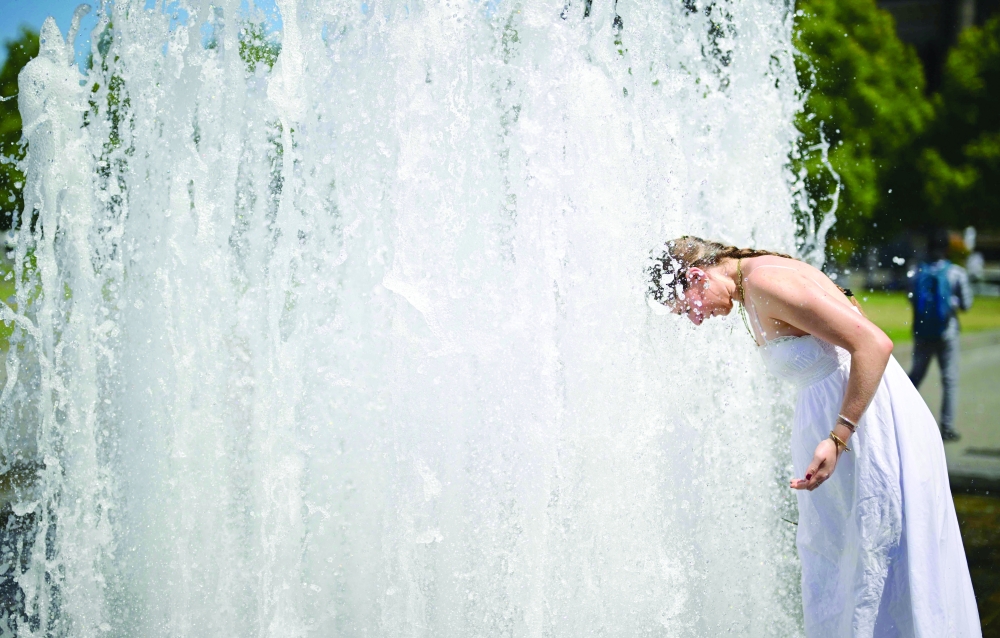 A young woman holds her head into the cool water of a fountain at the Lustgarten park on Museum Island in Berlin, as temperatures were predicted to reach up to 37 degrees Celsius. — AFP