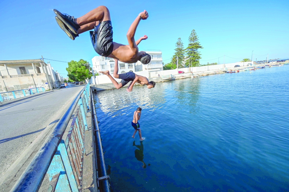 Youths dive into the sea at a beach off the La Goulette suburb of Tunis as summer holidays start in Tunisia. — AFP