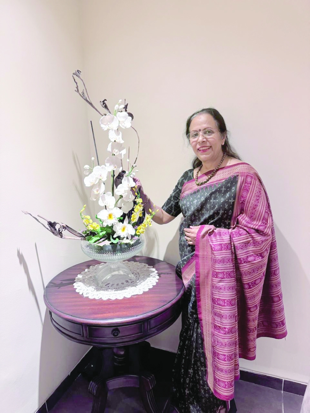 Artist Poornima Subramanian poses with phalenopsis orchid arrangement in a rustic style