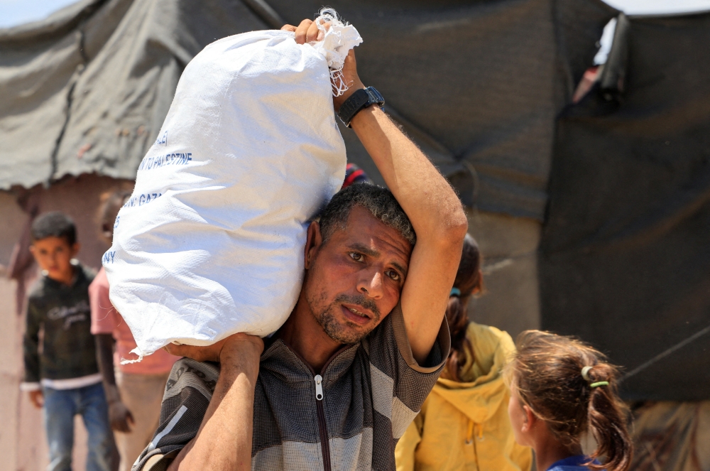 A Palestinian carries a sack of food items in Khan Younis. — Reuters