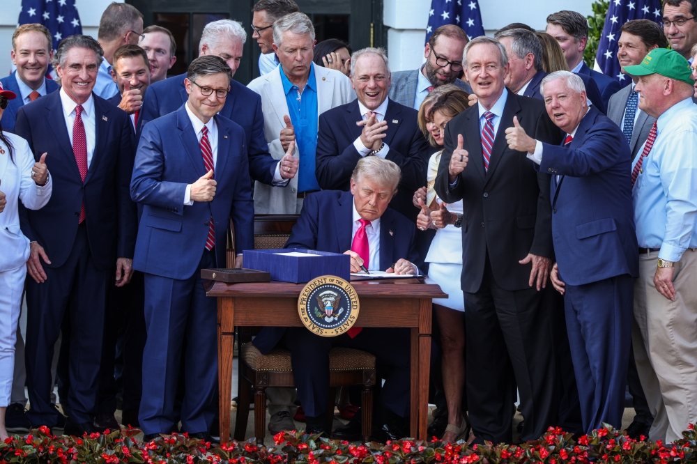 Members of Congress give thumbs up as President Donald Trump signs his signature policy bill  during a Fourth of July celebration event outside the White House in Washington, on Friday, July 4, 2025. (Valerie Plesch/The New York Times)
