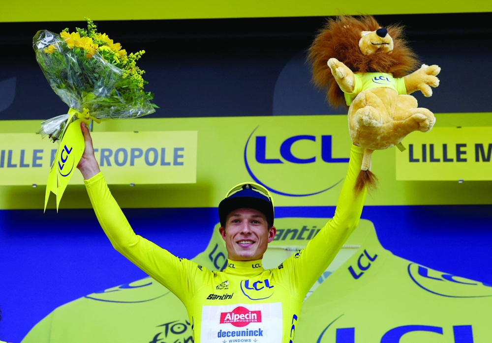 Jasper Philipsen celebrates on the podium wearing the yellow jersey after stage 1. — Reuters