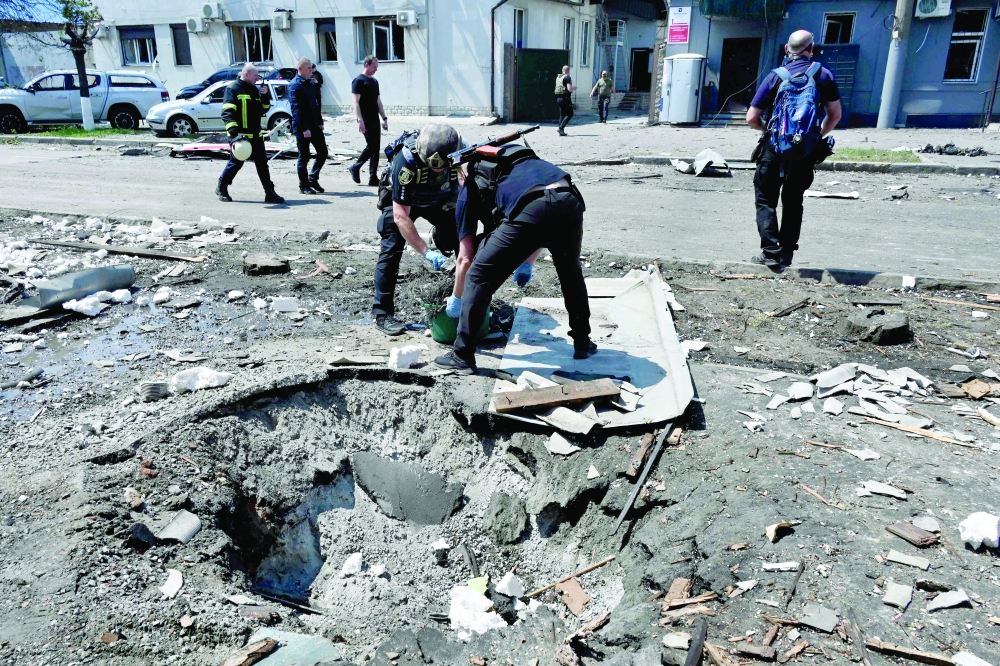 Ukrainian law enforcement officers work next to a crater following a drone attack in Kharkiv. — AFP