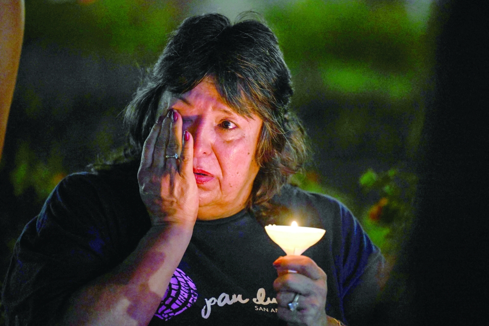 A woman wipes away tears during a vigil for the victims of the floods at Travis Park. — AFP