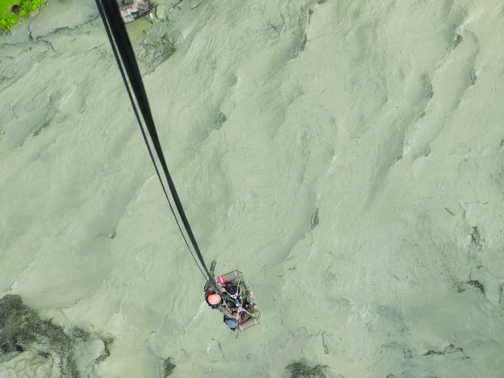 A member of the Nepalese army airlifts people stranded
