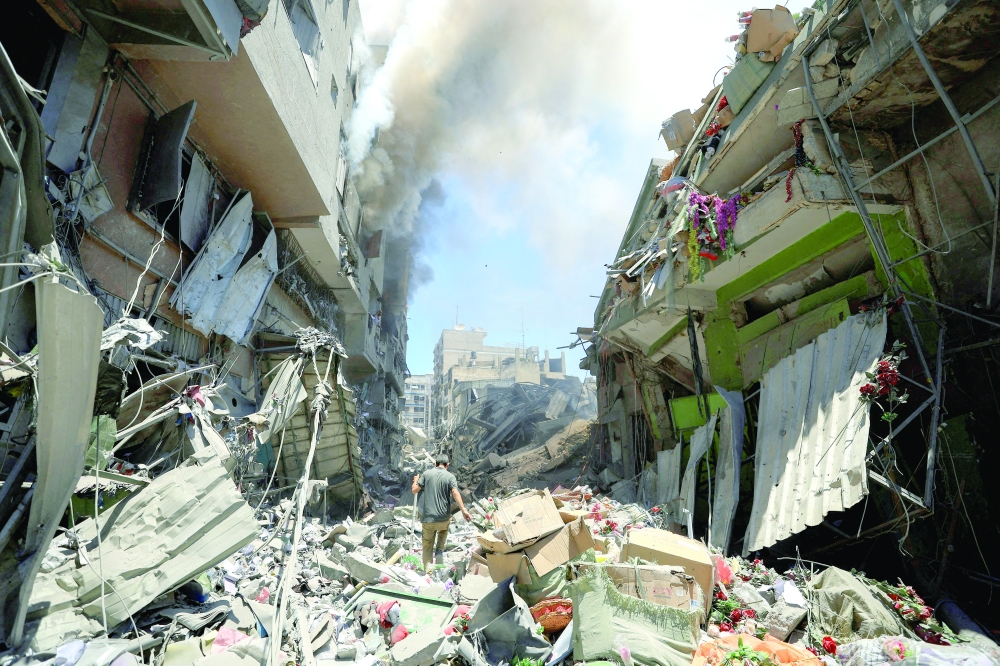 Smoke rises as a Palestinian man inspects the site of Israeli strikes on buildings at Gaza’s Old City market on Wednesday. — Reuters