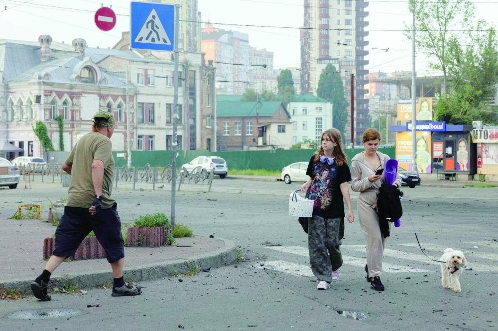 People leave a shelter with their belongings near a damaged shopping centre after a night of Russian strikes in Kyiv amid the Russian invasion in Ukraine. — AFP