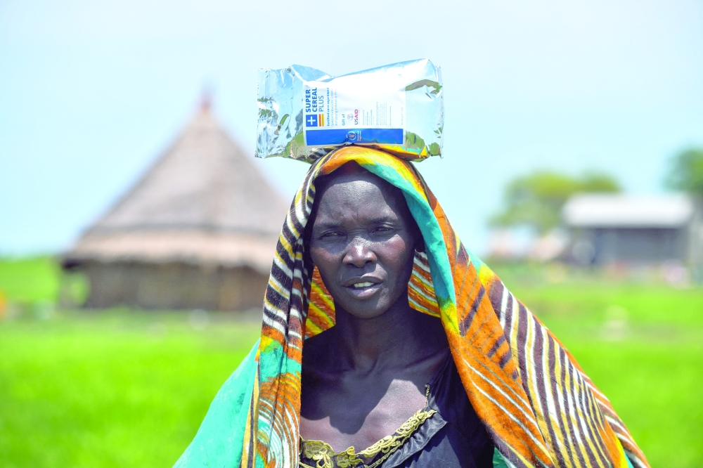 Nyakueiy Cleug, a South Sudanese woman carries a bag of cereal received as part of WFP's food assistance upon arrival at the Muon Reception Centre where she was screened, in Gambella region, Ethiopia. — Reuters