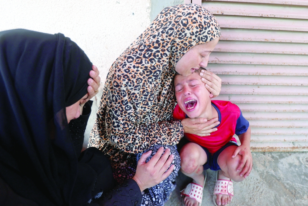 A Palestinian woman comforts a child as casualties are brought into Al Aqsa Martyrs Hospital following an Israeli strike, in Deir Al Balah, central Gaza Strip, on Thursday. — Reuters