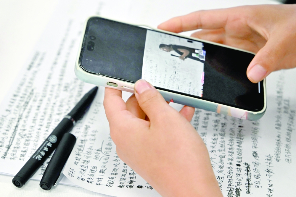 A participant with a notation photo on a phone alongside handwritten notes during a 'hands-on livestreaming bootcamp' for farmers at the rural revitalisation office in Penglai, Yantai city, China's eastern Shandong province. - AFP