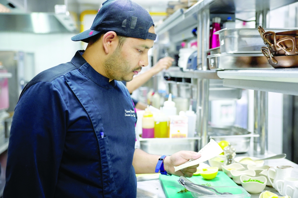 Chef Khimraj Nepali looks at the recipe taken from 'Aiman', the AI Chef. - Reuters