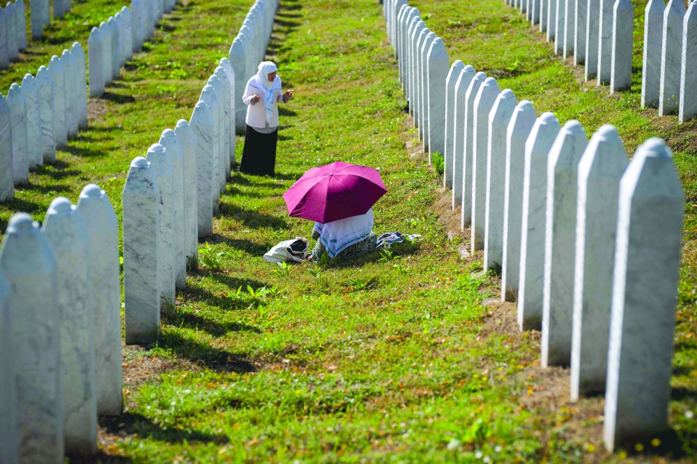 People stand near gravestones at the memorial cemetery in the village of Potocari, near the eastern Bosnian town of Srebrenica. Thousands of mourners on Friday commemorated in Srebrenica the genocide committed 30 years ago by Bosnian Serb forces, one of Europe's worst atrocities since World War II. The victims of Srebrenica, which was at the time a UN-protected enclave, were buried in mass graves. So far about 7,000 victims have been identified and buried while about 1,000 are still missing. — AFP