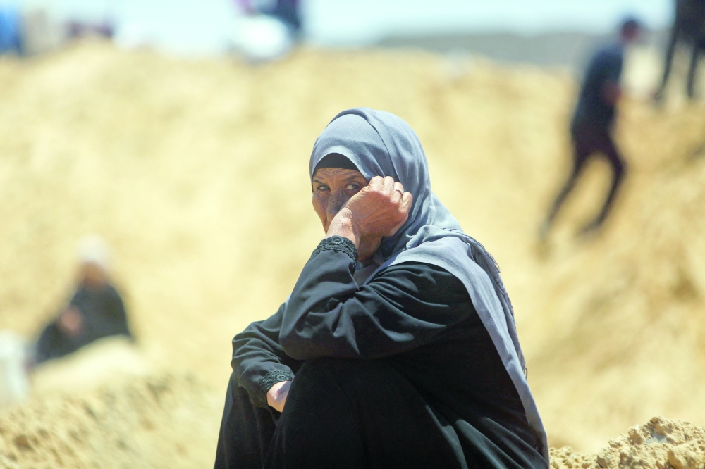 A woman looks on as Palestinians inspect a reported incursion by Israeli tanks, in Gaza. — AFP