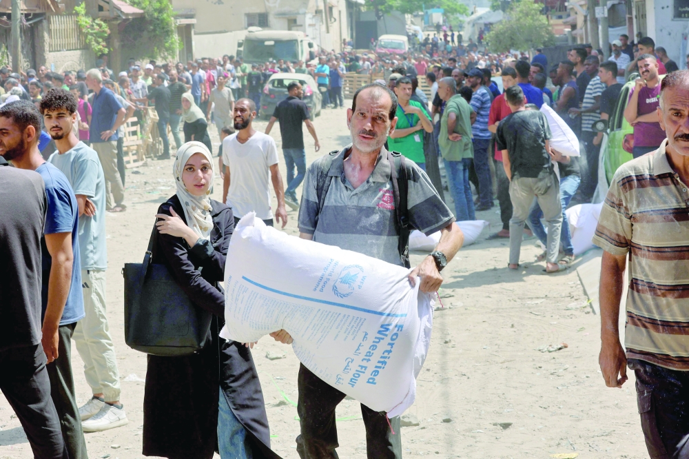 A man carries a bag of flour at a UN World Food Programme (WFP) warehouse on Al Jalaa street in Gaza City on Saturday. — AFP