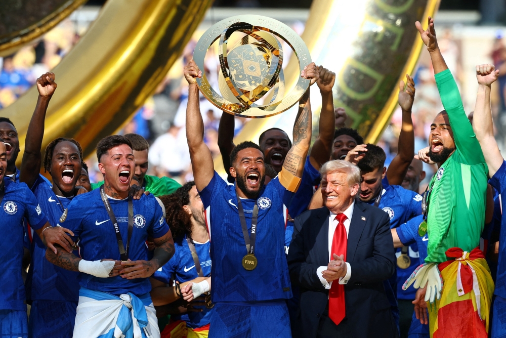 Soccer Football - FIFA Club World Cup - Final - Chelsea v Paris St Germain - MetLife Stadium, East Rutherford, New Jersey, U.S. - July 13, 2025 Chelsea's Reece James lifts the trophy as he celebrates with teammates after winning the FIFA Club World Cup, U.S. President Donald Trump looks on REUTERS/Kai Pfaffenbach     TPX IMAGES OF THE DAY

