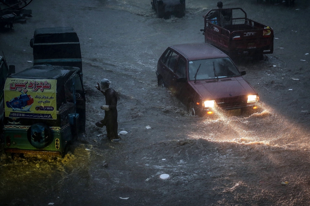 Commuters make their way through a flooded road