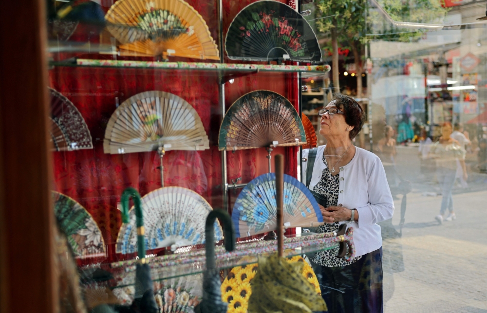 A woman looks at the window of Casa de Diego hand fan store in Madrid, on July 8, 2025.  The Spanish must-have fan has retained its relevance amid increasingly oppressive summer temperatures stoked by climate change. (Photo by Thomas COEX / AFP)

