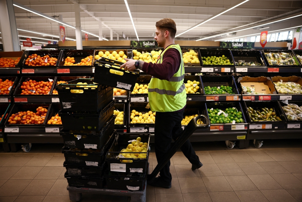 An employee arranges produce inside a supermarket in Richmond, west London, Britain. — Reuters