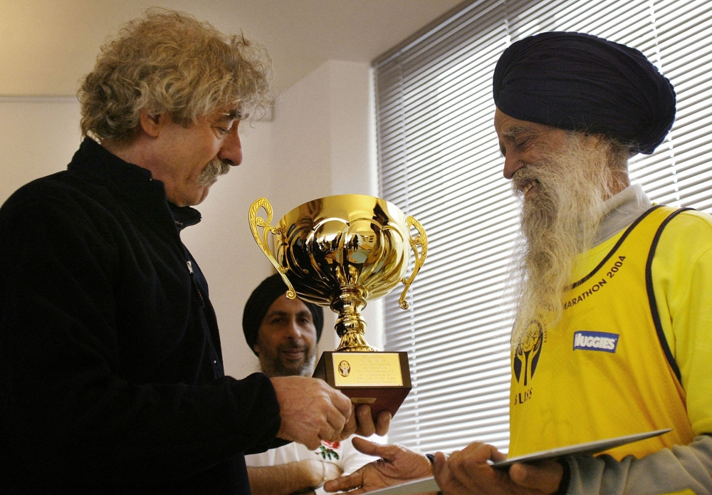 (FILES) Ninty three-year-old Fauja Singh (R), the oldest runner in this year's Flora London marathon, recieves an award in recognition of his outstanding running achievements and also marking his 93rd birthday from David Bedford, the Flora London Marathon race director, 01 April 2004, at Marasthon House in London. India's Fauja Singh, believed to be the world's oldest distance runner, has died in a road accident aged 114, his biographer said on July 15, 2025. (Photo by Jim WATSON / AFP)

