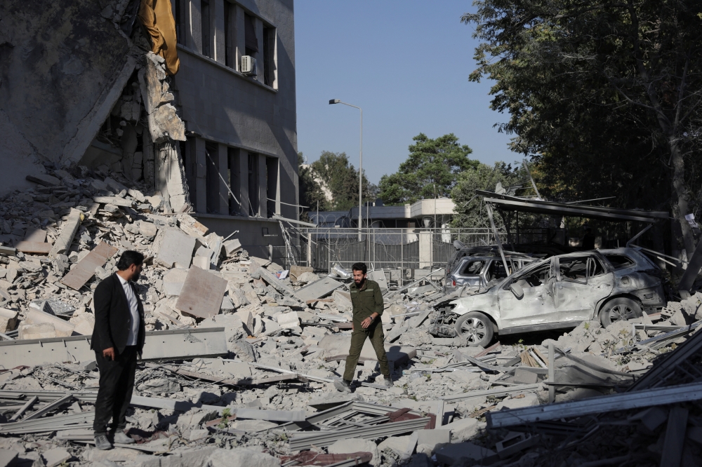 Men walk among debris after powerful Israeli airstrikes shook Damascus on Wednesday, — Reuters