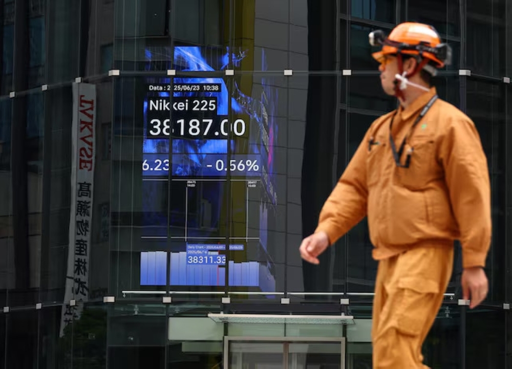 A man walks past an electronic board showing the Nikkei share average in Tokyo, Japan. — Reuters