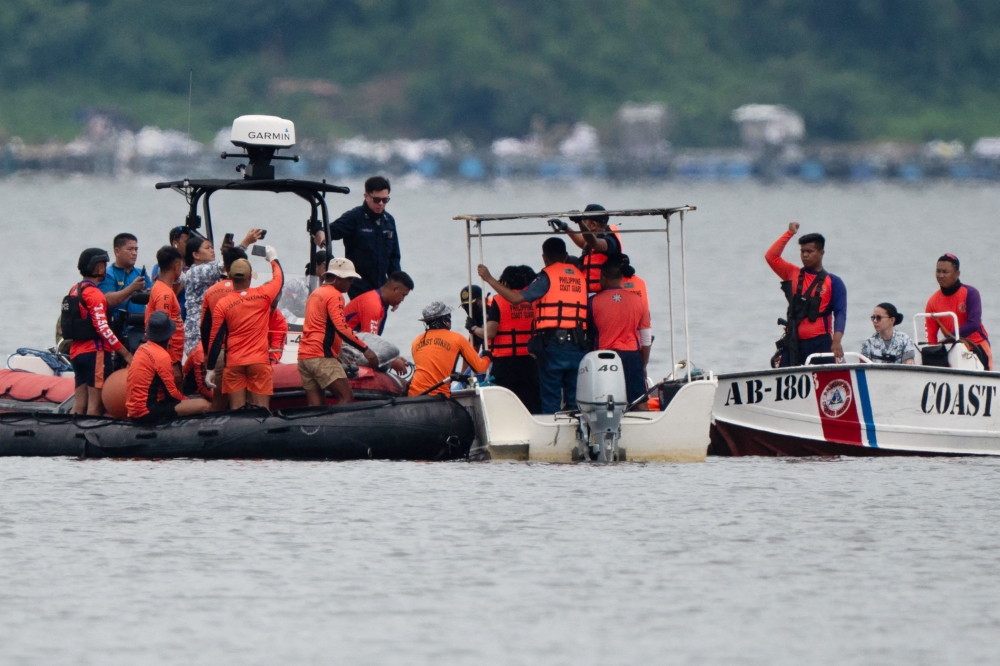 Philippine Coast Guard personnel retrieve a sack during the search for missing cockfighters, allegedly killed by rogue police, in Taal lake near Laurel town, Batangas province. — AFP