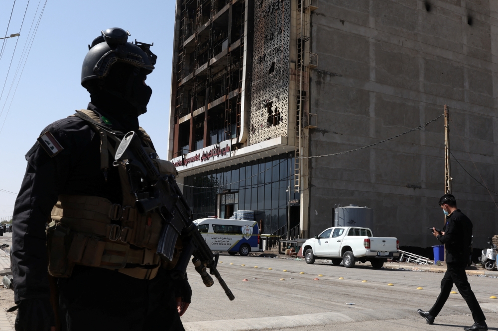 A member of security forces stands guard near the wreckage of a shopping center, after a massive overnight fire killed dozens of people, in al-Kut, Wasit province, Iraq, July 17, 2025. REUTERS/Ahmed Saad