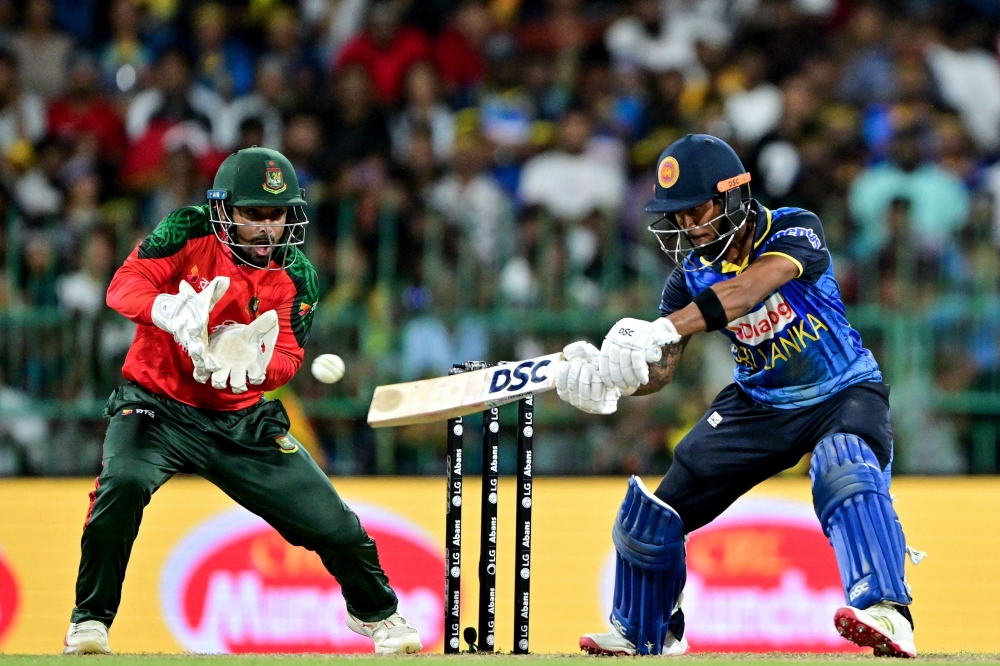 Sri Lanka's Pathum Nissanka (R) plays a shot as Bangladesh's wicketkeeper and captain Litton Das reacts during the third and final Twenty20 international cricket match between Sri Lanka and Bangladesh at the R. Premadasa International Cricket Stadium in Colombo on July 16, 2025.  (Photo by Ishara S. KODIKARA / AFP)

