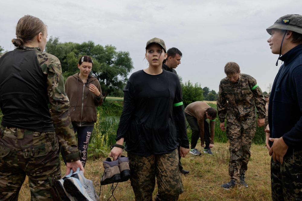 Participants stand with their shoes in hand at the Pidpillya intensive training camp in the Kyiv region. — AFP