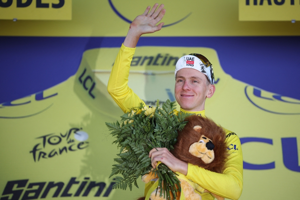 UAE Team Emirates - XRG team's Slovenian rider Tadej Pogacar celebrates on the podium with the overall leader's yellow jersey after the 13th stage. — AFP