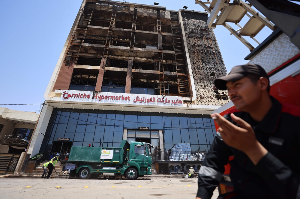 A cleaning operation starts outside the charred building, in Kut. — AFP