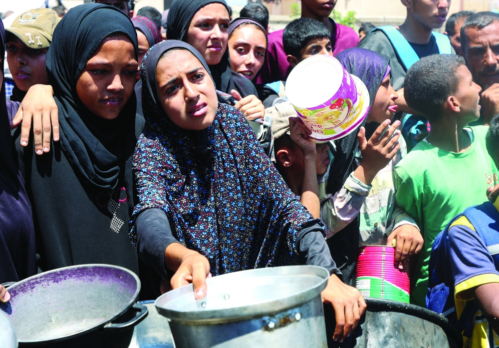 Palestinians gather to receive food from a charity kitchen, amid a hunger crisis, in Nuseirat on Sunday. — Reuters