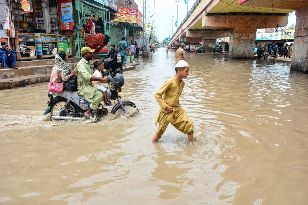 People wade through a flooded street after heavy monsoon rains in Hyderabad
