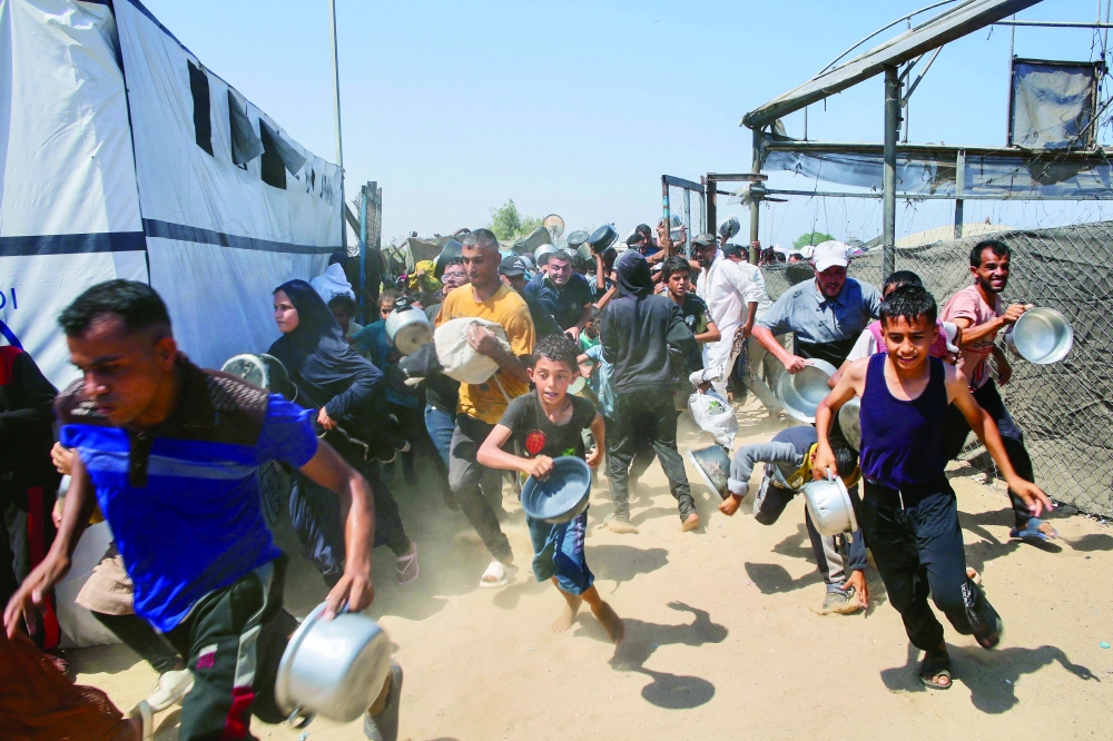 Palestinian children wait for a meal at a charity kitchen in the Mawasi area of Khan Yunis. — AFP