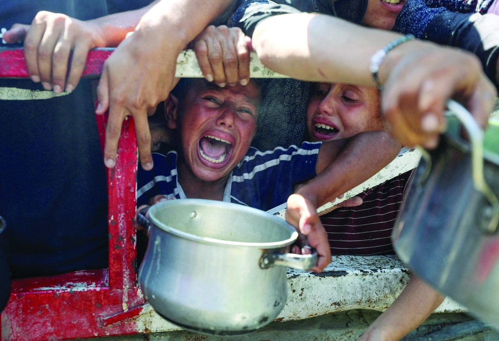
Palestinians wait to receive food from a charity kitchen in Gaza City on Wednesday. — Reuers 