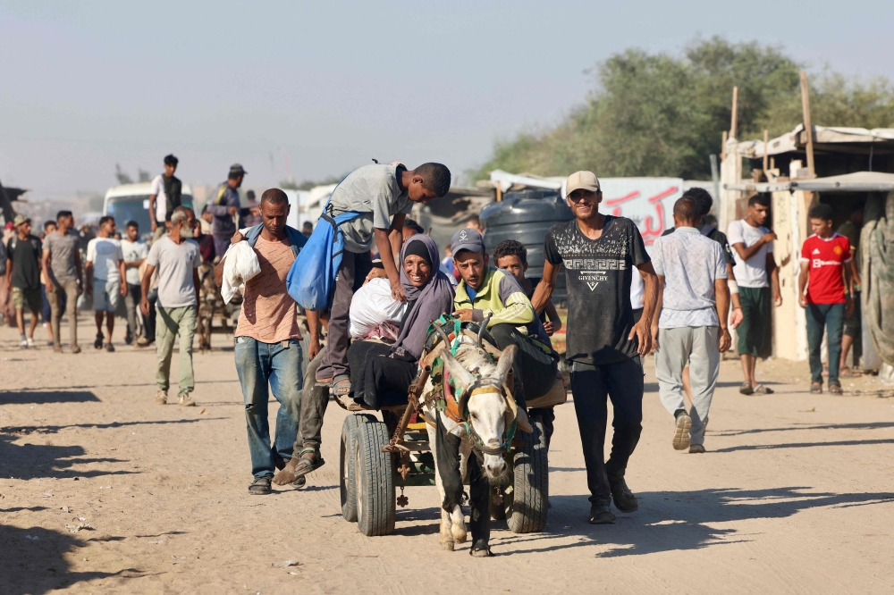 Palestinians make their way in the Mawasi area of Rafah on July 24, 2025, after receiving humanitarian aid