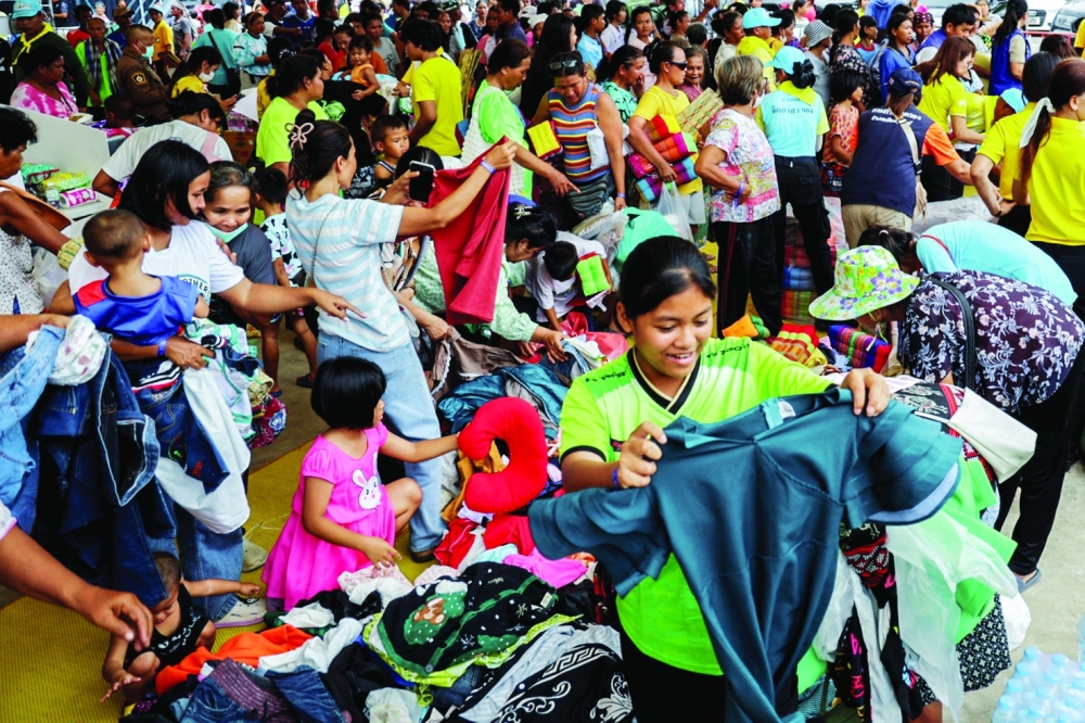 People search for clothes at a pile of donated items at a shelter. According to authorities people have been killed across three border provinces, in Buriram province, Thailand. - Reuters