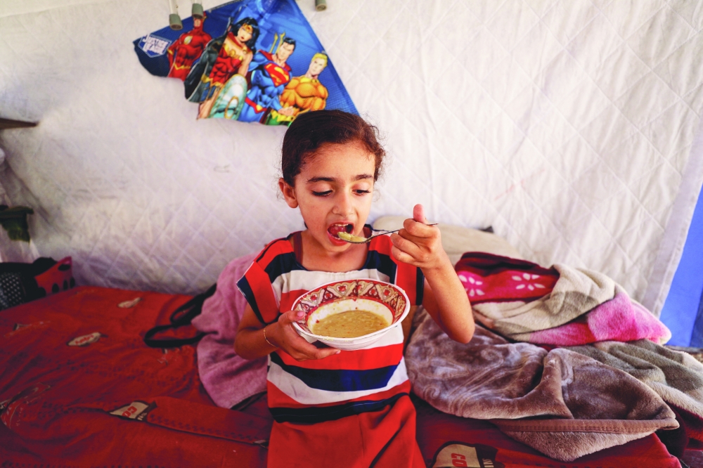 
Eyala, the daughter of displaced Palestinian man Nizar Bakron, eats inside their tent, in Gaza City. — Reuters 