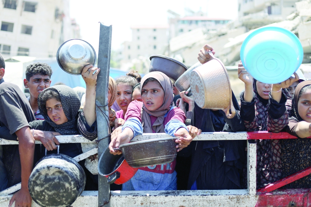 
Palestinians wait to receive food from a charity kitchen, amid a hunger crisis, in Gaza on Thursday. — Reuters 