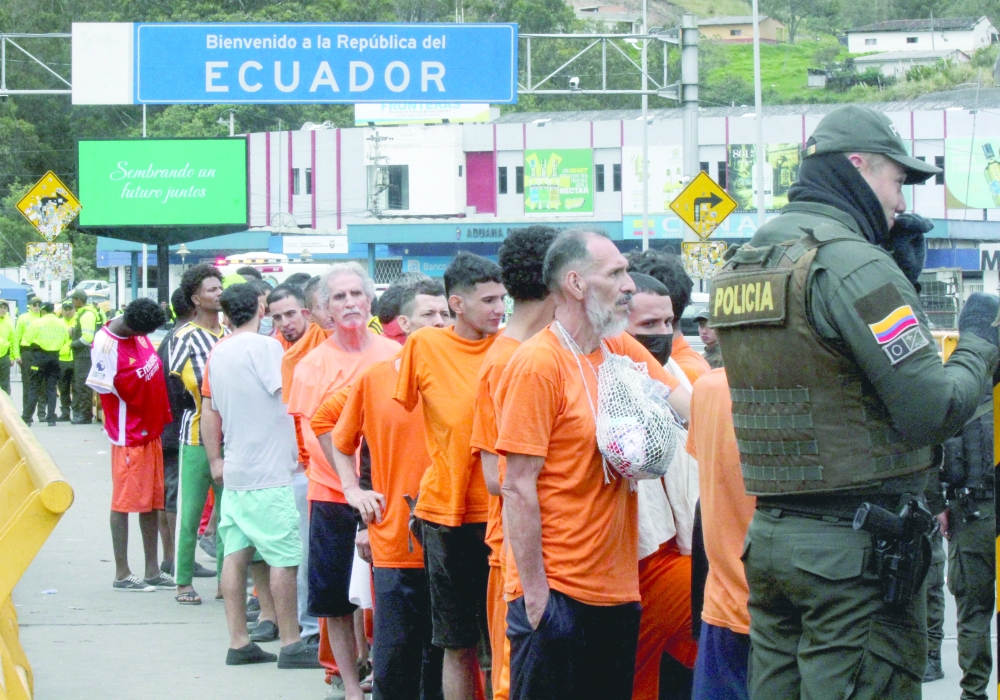 Inmates queue up before being deported to Colombia at the Rumichaca international bridge, Colombia. — AFP