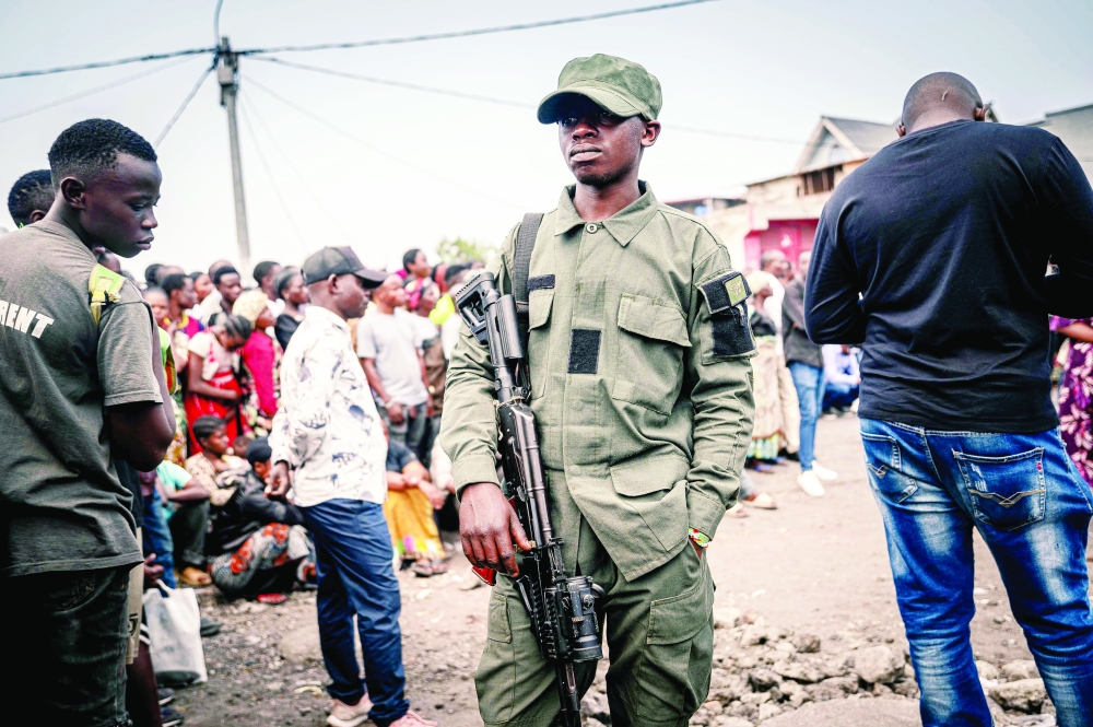 A soldier stands guard with a Kalashnikov rifle in front of the gathered crowd, in Goma. — AFP