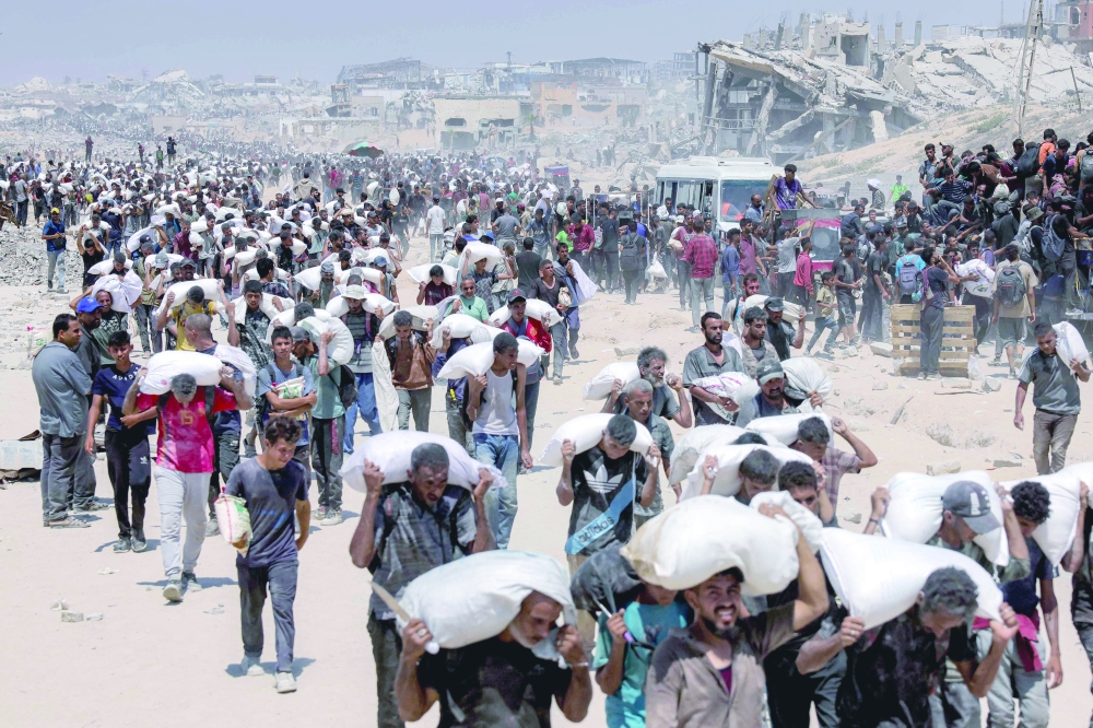 People walk with sacks of flour delivered after trucks carrying humanitarian aid entered northern Gaza. — AFP