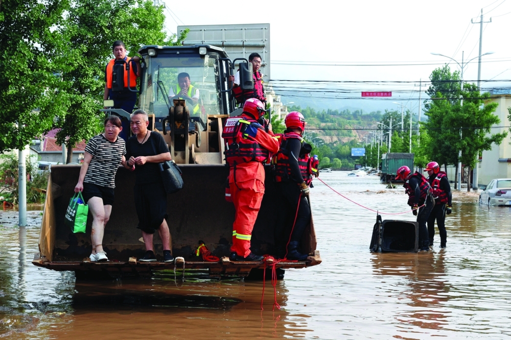 Rescue workers set up a barrier to cover a manhole in the middle of a flooded road, in Miyun district of Beijing. — Reuters